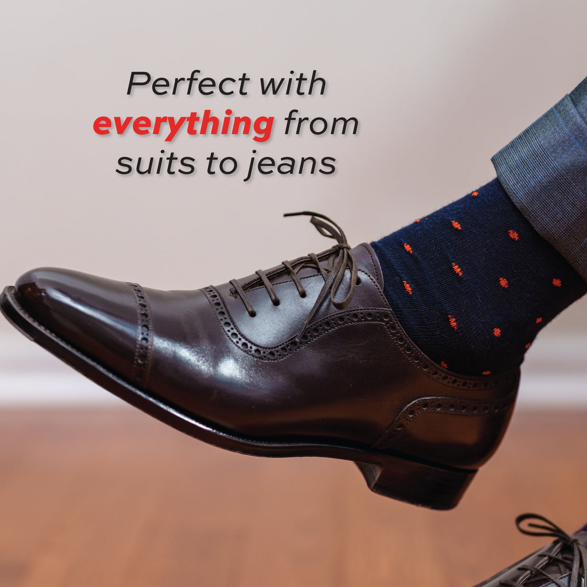 man's left foot wearing oxfords and navy over the calf wool dress socks with orange dots with "perfect with everything"  text overlay