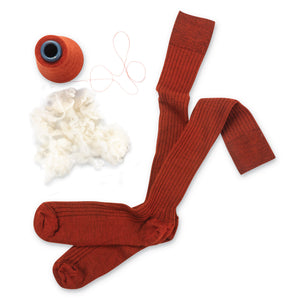 pair of orange merino wool over the calf mens dress socks laying on a white background with yarn and wool next to them