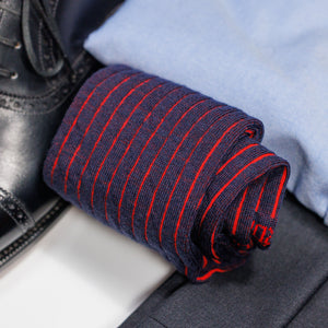 rolled up pair of navy and red shadow stripe dress socks atop charcoal slacks