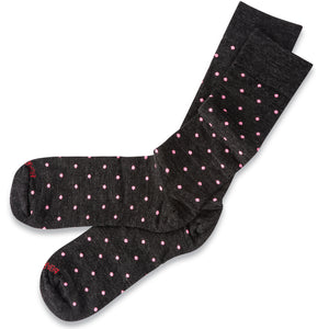 pair of mid-calf length charcoal grey dress socks decorated with bright pink polka dots atop white table