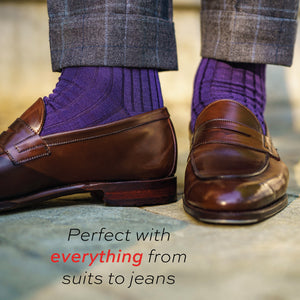 close up image of a man wearing brown loafers and purple merino wool mid-calf length dress socks