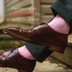 man sitting down wearing pink merino wool over the calf ribbed mens dress socks and brown dress socks