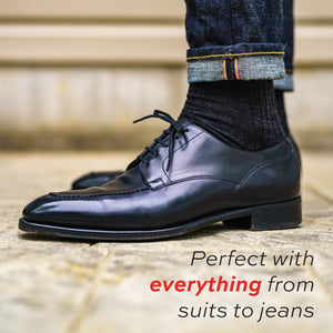 foot wearing jeans, nice shoes, and black wool dress socks with 