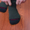 man sliding on pair of navy and green houndstooth dress socks