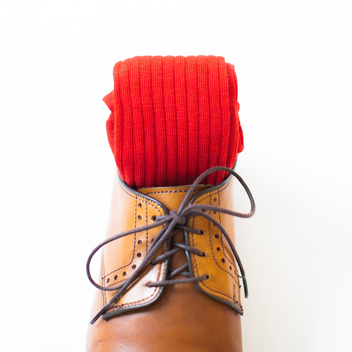 red dress socks rolled up in light brown men&#39;s dress shoes