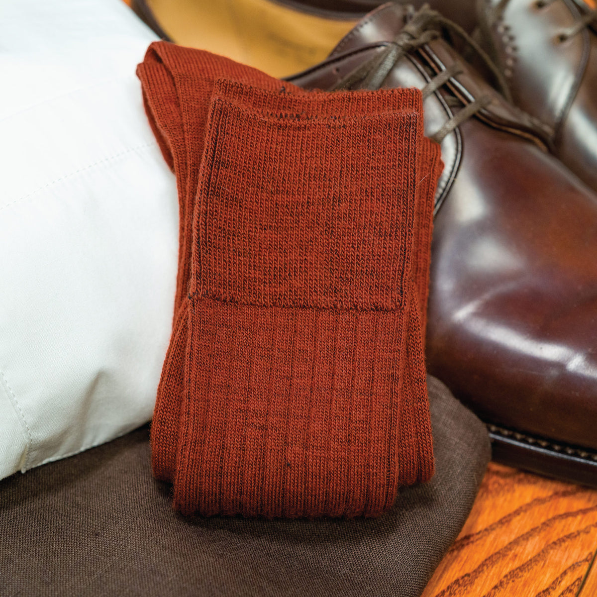 pair of Burnt Orange Merino Wool Mid Calf Dress Socks laying on top of nice clothing
