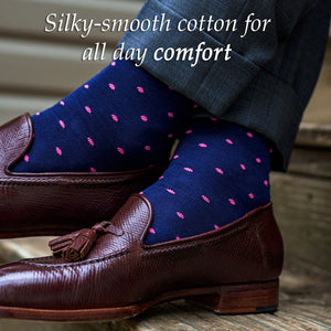 man wearing navy cotton dress socks decorated with bright pink polka dots crossing ankles