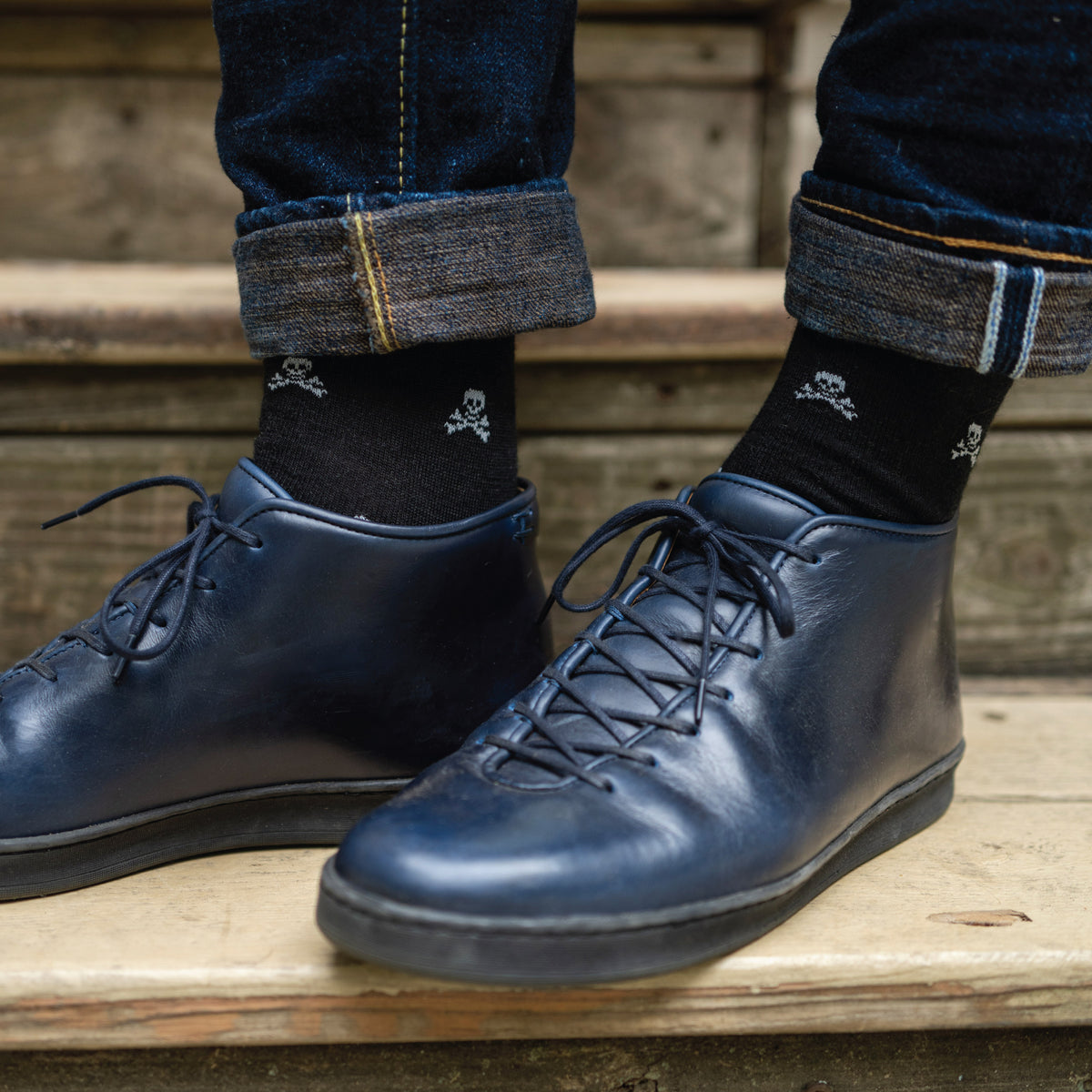 man wearing jeans and skull and bones patterned merino wool over the calf dress socks
