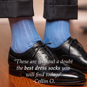 man wearing light blue ribbed dress socks with charcoal slacks and black oxfords standing on hardwood floor