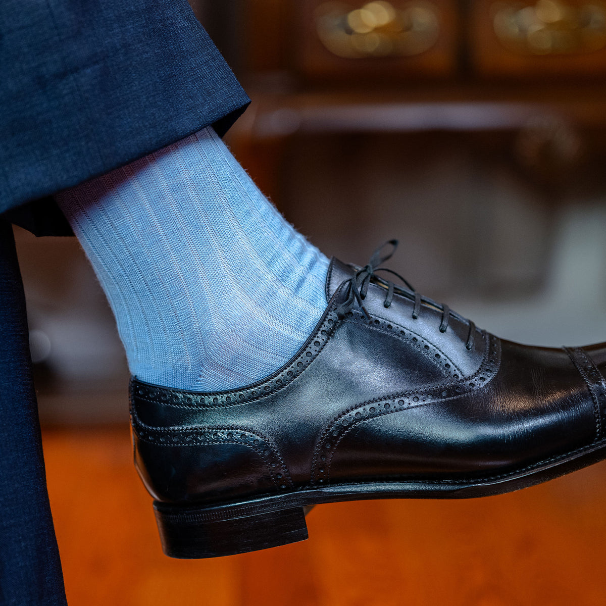 man wearing black dress shoes and sky blue wool mid-calf dress socks