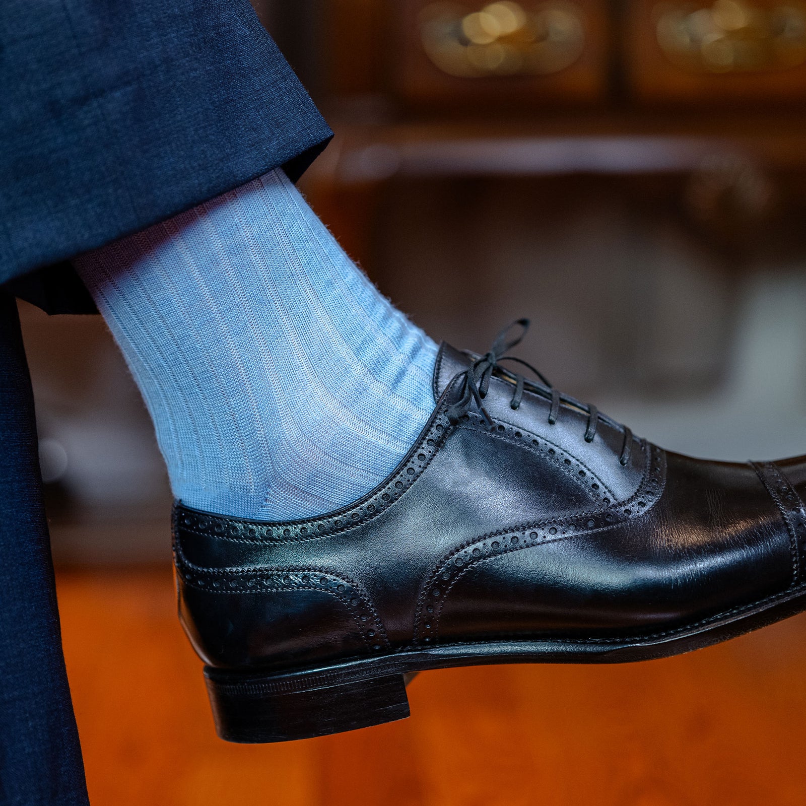 man wearing black dress shoes and sky blue wool mid-calf dress socks