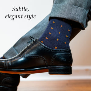 man crossing legs wearing orange and navy patterned wool dress socks