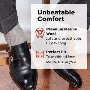man sitting on stool wearing ight grey merino wool over the calf dress socks and black dress shoes