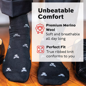 man wearing skull and bones patterned over the calf merino wool dress socks standing on a wood floor