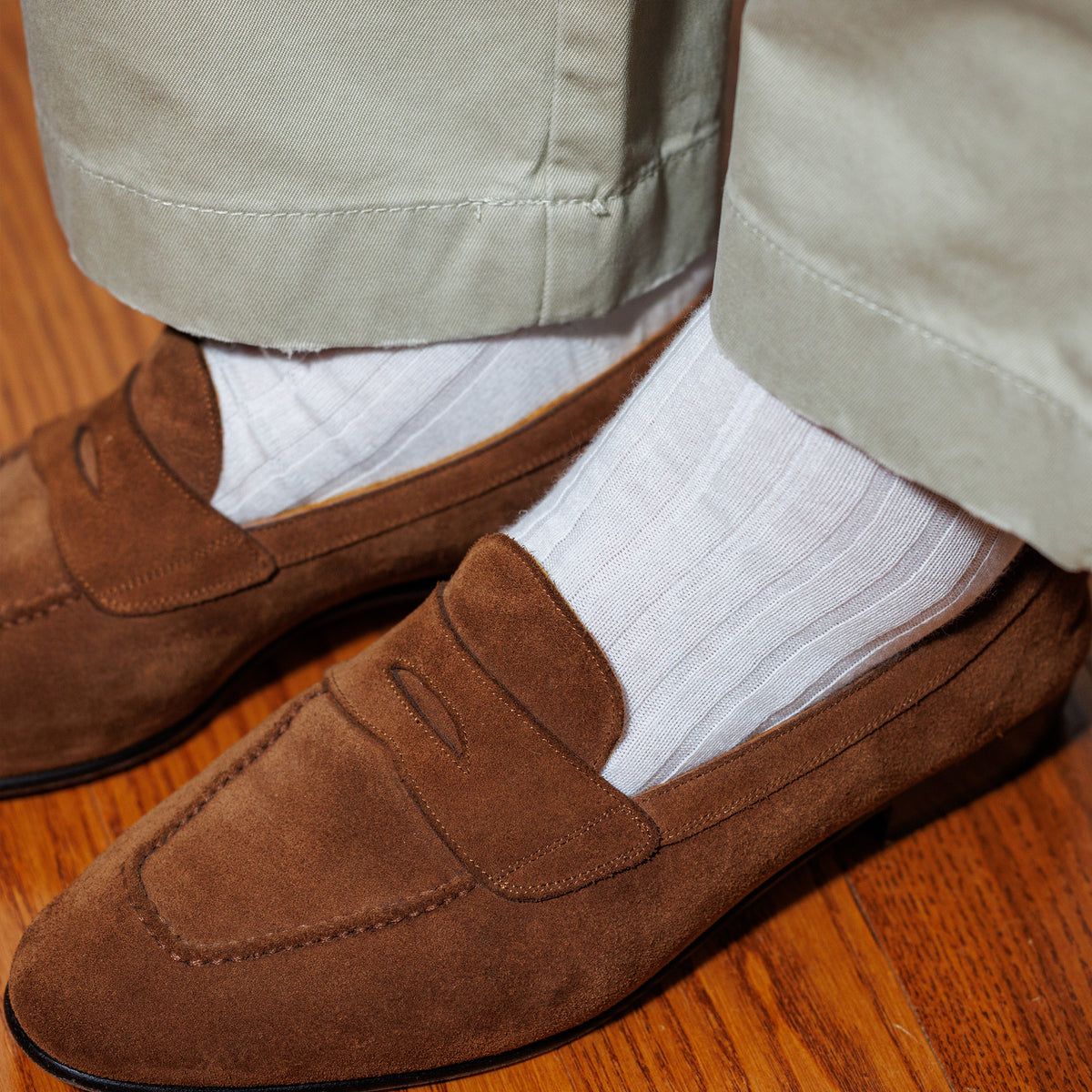 man standing wearing white ribbed merino wool dress socks and brown loafers