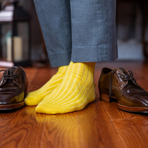 man wearing yellow dress socks standing on hardwood floor