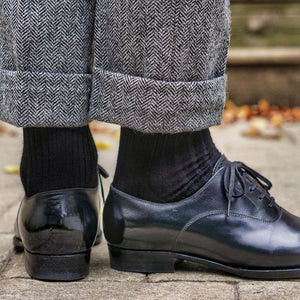 Man Wearing Black Merino Wool Dress Socks with Grey Herringbone Trousers and Black Dress Shoes