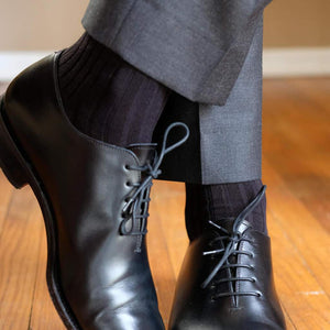 Man Crossing Ankles Wearing Black Dress Socks with Charcoal Dress Pants and Black Dress Shoes