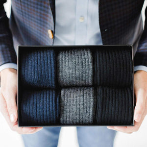 Man Wearing Sportcoat Holding Box Filled with Black Grey and Navy Dress Socks