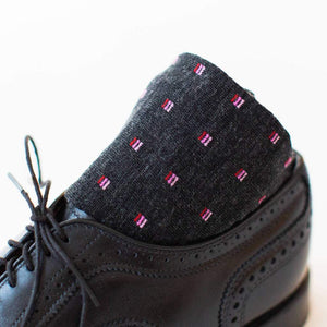 Pair of Patterned Charcoal Wool Dress Socks Rolled Up Sitting in Black Brogue Dress Shoes