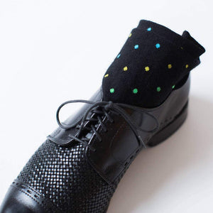 Pair of Black Patterned Dress Socks Rolled Up in a Black Dress Shoes