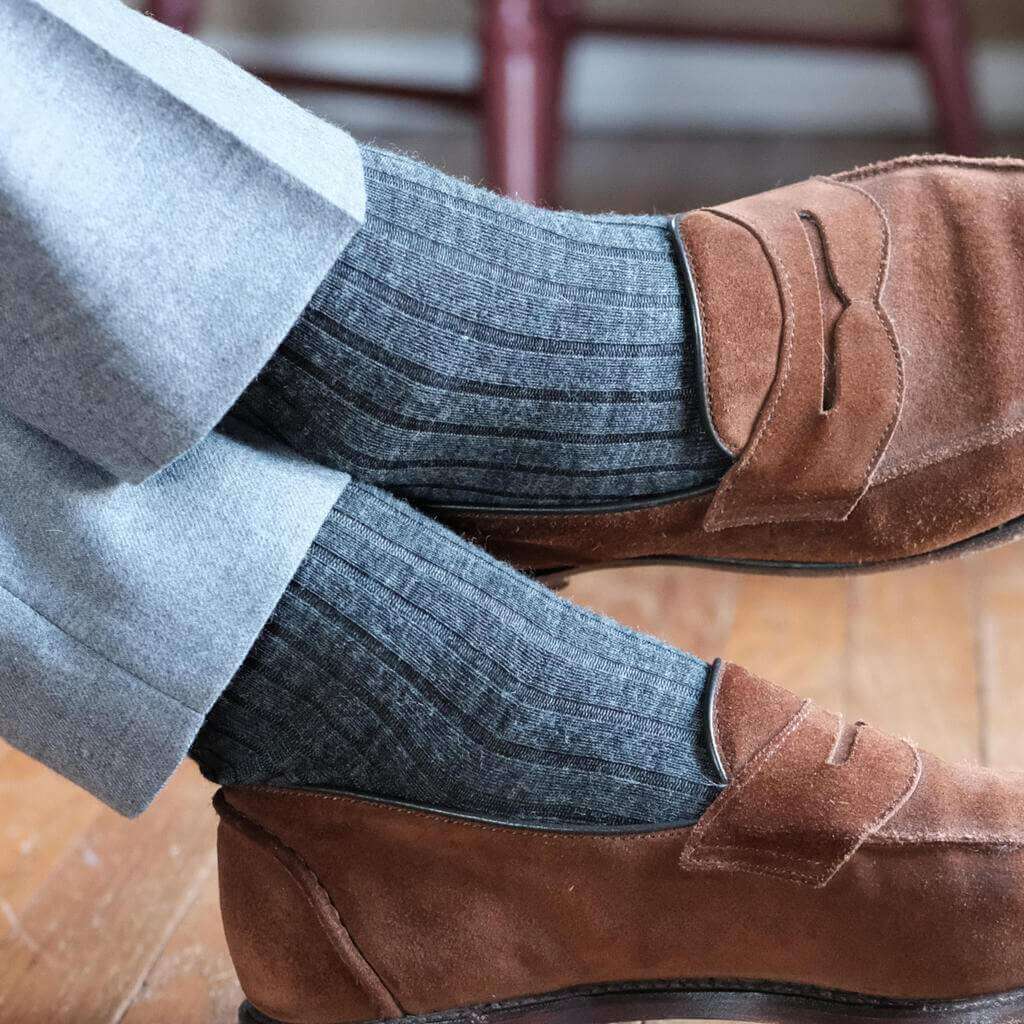 Man Crossing Ankles Wearing Grey Dress Socks with Charcoal Dress Pants and Dark Brown Suede Dress Shoes