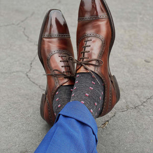 Man Crossing Ankles Wearing Charcoal Patterned Dress Socks with Navy Dress Pants and Brown Captoe Dress Shoes