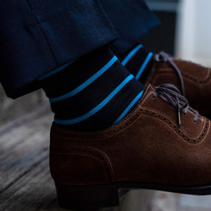 man sitting on stairs wearing black dress socks with bright blue stripes