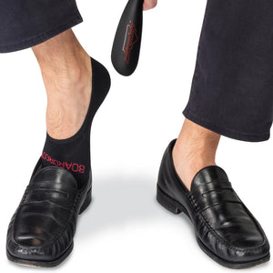 man wearing black wool no-show socks with black penny loafers and navy blue chinos