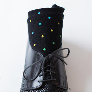 black merino wool over the calf dress socks decorated with colorful polka dots rolled up and placed inside a black dress shoe