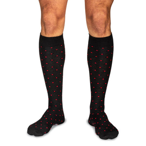 model wearing black over the calf dress socks decorated with bright red dots