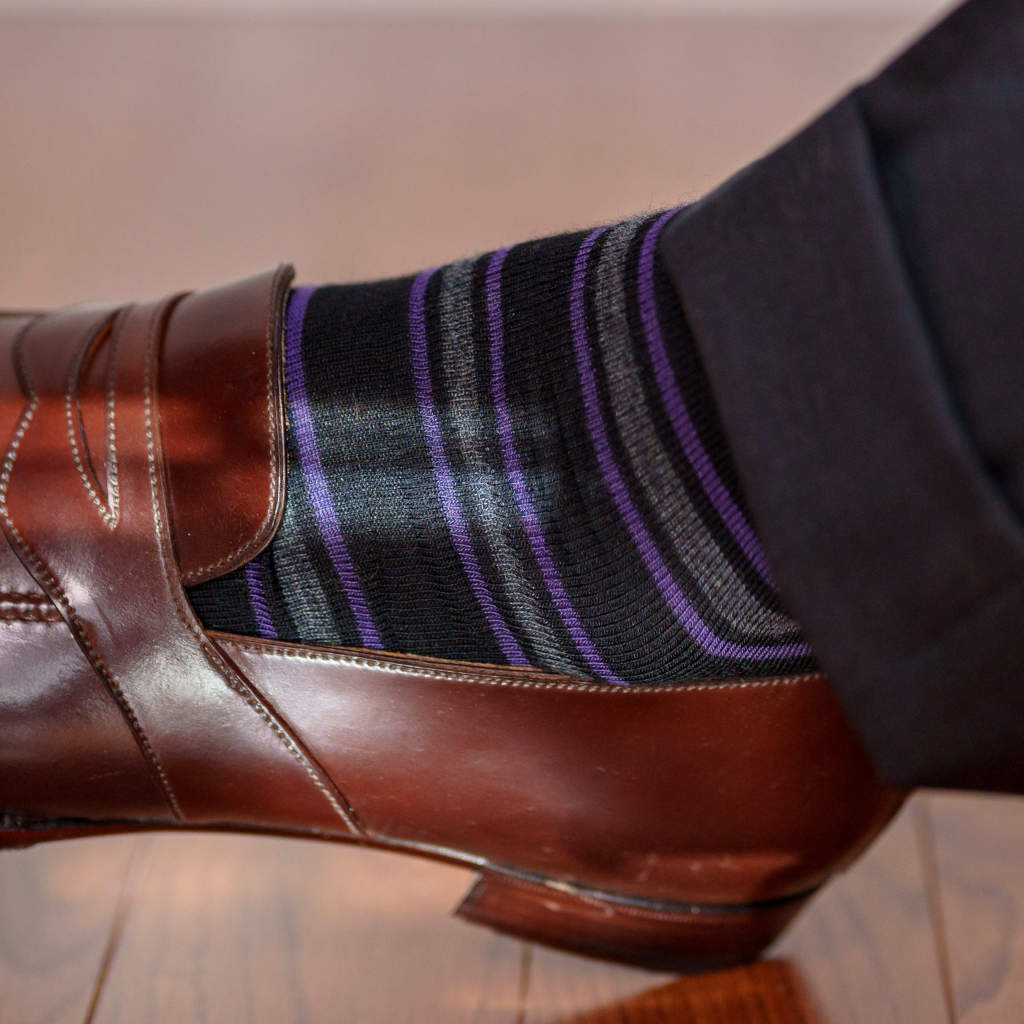 purple grey and black horizontal striped dress socks with grey trousers and brown penny loafers