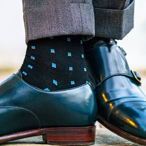 black dress socks decorated with blue squares paired with grey dress pants and blue monkstrap shoes