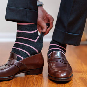 man wearing light pink and dark grey striped dress socks using shoe horn to put on penny loafers