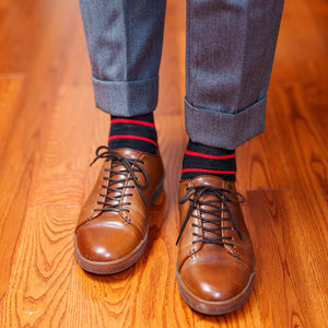 man wearing dark grey and red striped dress socks paired with light grey trousers and brown leather sneakers