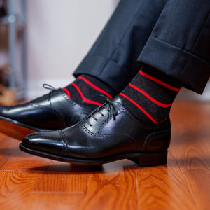 charcoal grey dress socks decorated with bright red horizontal stripes paired with black oxfords and dark grey trousers
