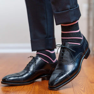 man taking a step wearing grey and pink striped dress socks with black captoe oxfords