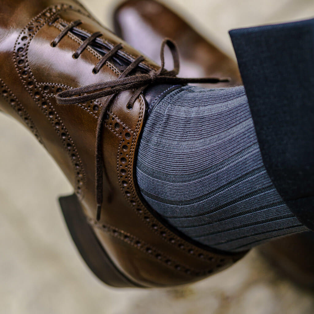 grey dress socks for men paired with charcoal trousers and dark brown brogue dress shoes