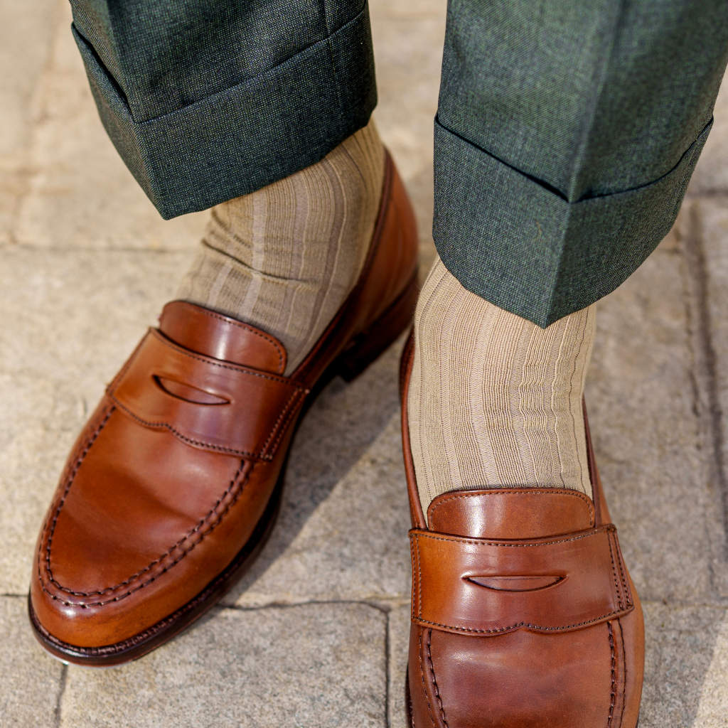 man standing wearing khaki cotton dress socks with light brown penny loafers and cuffed green trousers