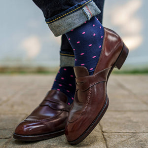 man crossing ankles wearing navy dress socks with bright pink dots