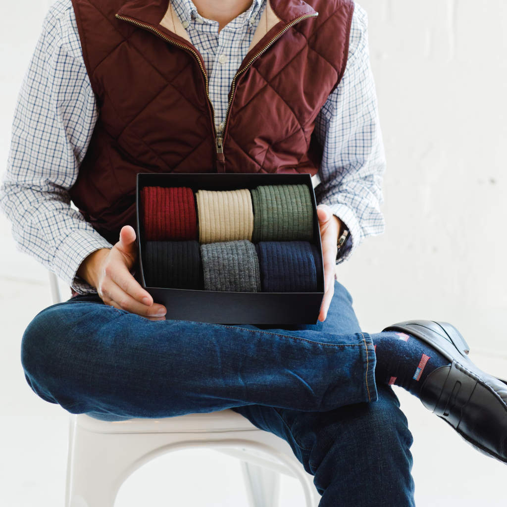 man holding gift box full of colorful merino wool dress socks