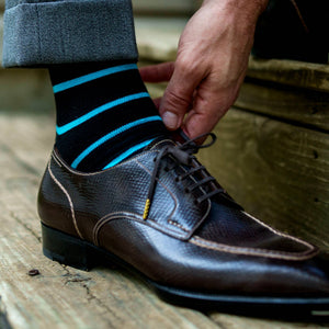man wearing black dress socks with bright blue horizontal stripes bending down and tying shoes