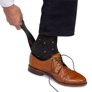 man using black metal shoe horn to put on light brown leather dress shoes