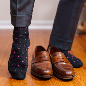 man walking on hardwood floor wearing dark grey dress socks decorated with bright pink dots