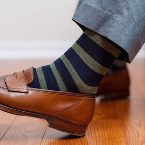 navy dress socks with olive green horizontal stripes paired with light grey trousers and light brown penny loafers