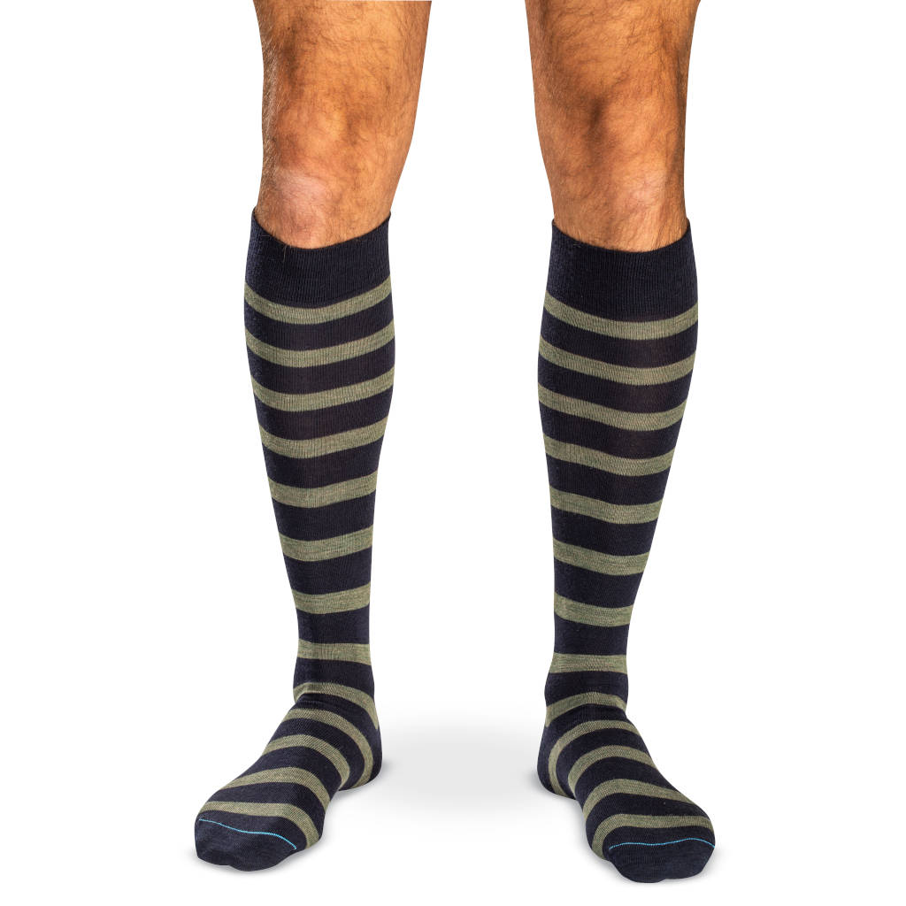 model wearing navy merino wool over the calf dress socks decorated with horizontal olive green stripes