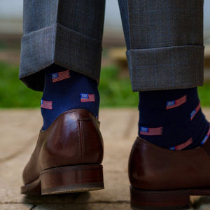 man walking wearing navy American flag dress socks with light grey trousers and brown dress shoes