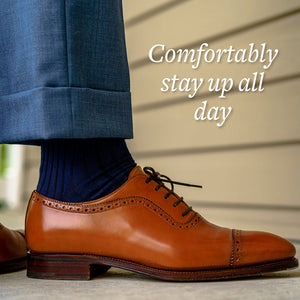 man standing wearing navy blue cotton dress socks and light brown leather dress shoes