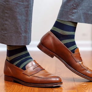man wearing navy dress socks decorated with olive green stripes taking a step on hardwood floors