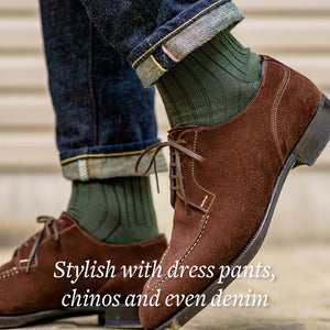 man walking wearing olive green cotton dress socks with dark blue jeans and brown suede dress shoes